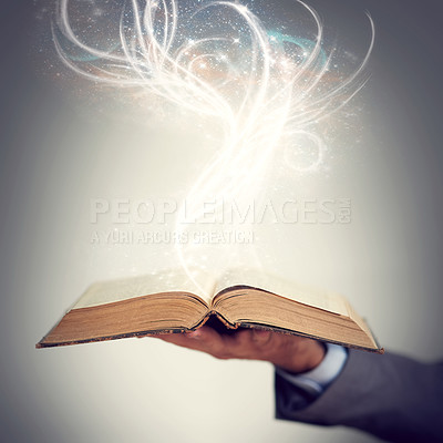 Buy stock photo Shot of a hand holding an open storybook with light emanating from it