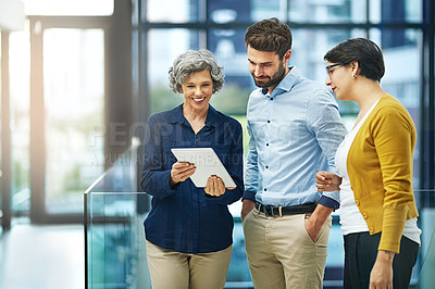 Buy stock photo Shot of a group of creative businesspeople looking at a tablet together in the office