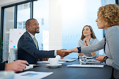 Buy stock photo Shot of two corporate businesspeople shaking hands during a meeting in the boardroom