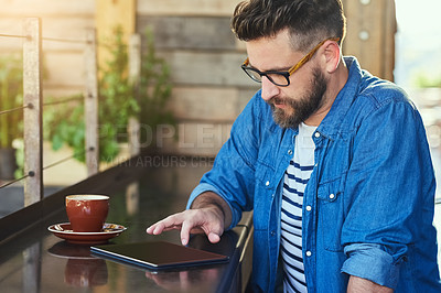 Buy stock photo Cropped shot of a handsome young man working on a digital tablet in a cafe