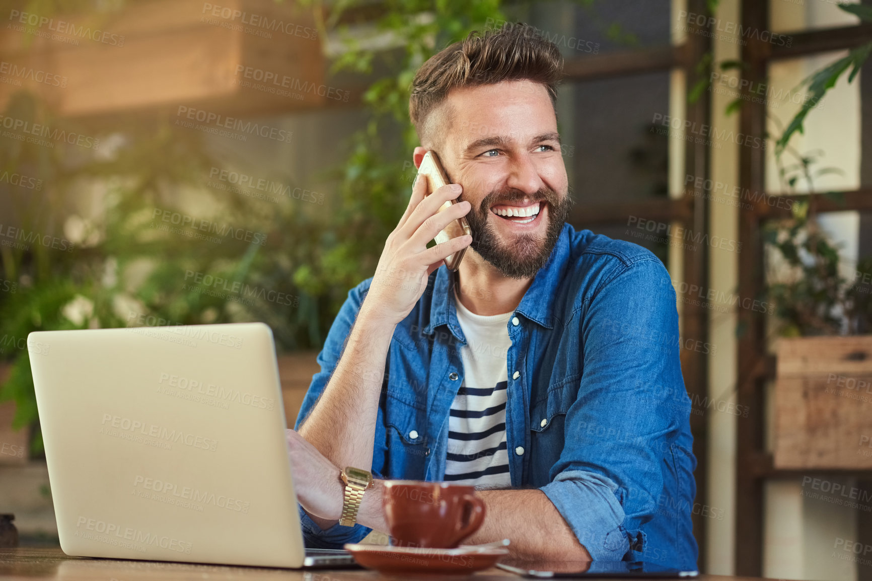 Buy stock photo Cropped shot of a handsome young man talking on a cellphone in a cafe