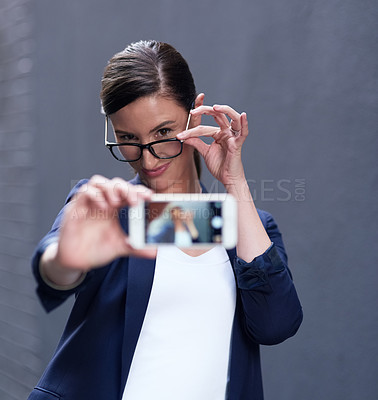 Buy stock photo Businesswoman, selfie and cellphone by dark background for online company, social media and pride. Confident female person, technology and glasses with emoji face for internet and profile picture 