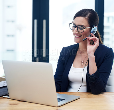 Buy stock photo Shot of a happy businesswoman talking on her headset while working on her laptop in the office