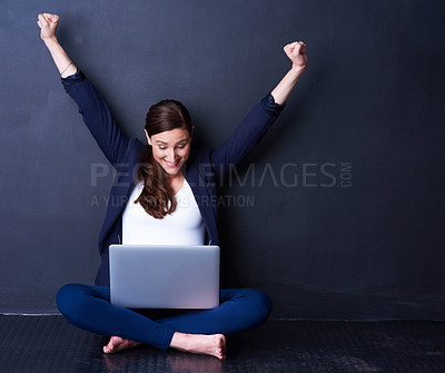 Buy stock photo Shot of a happy businesswoman looking at her laptop while raising her hands in excitement