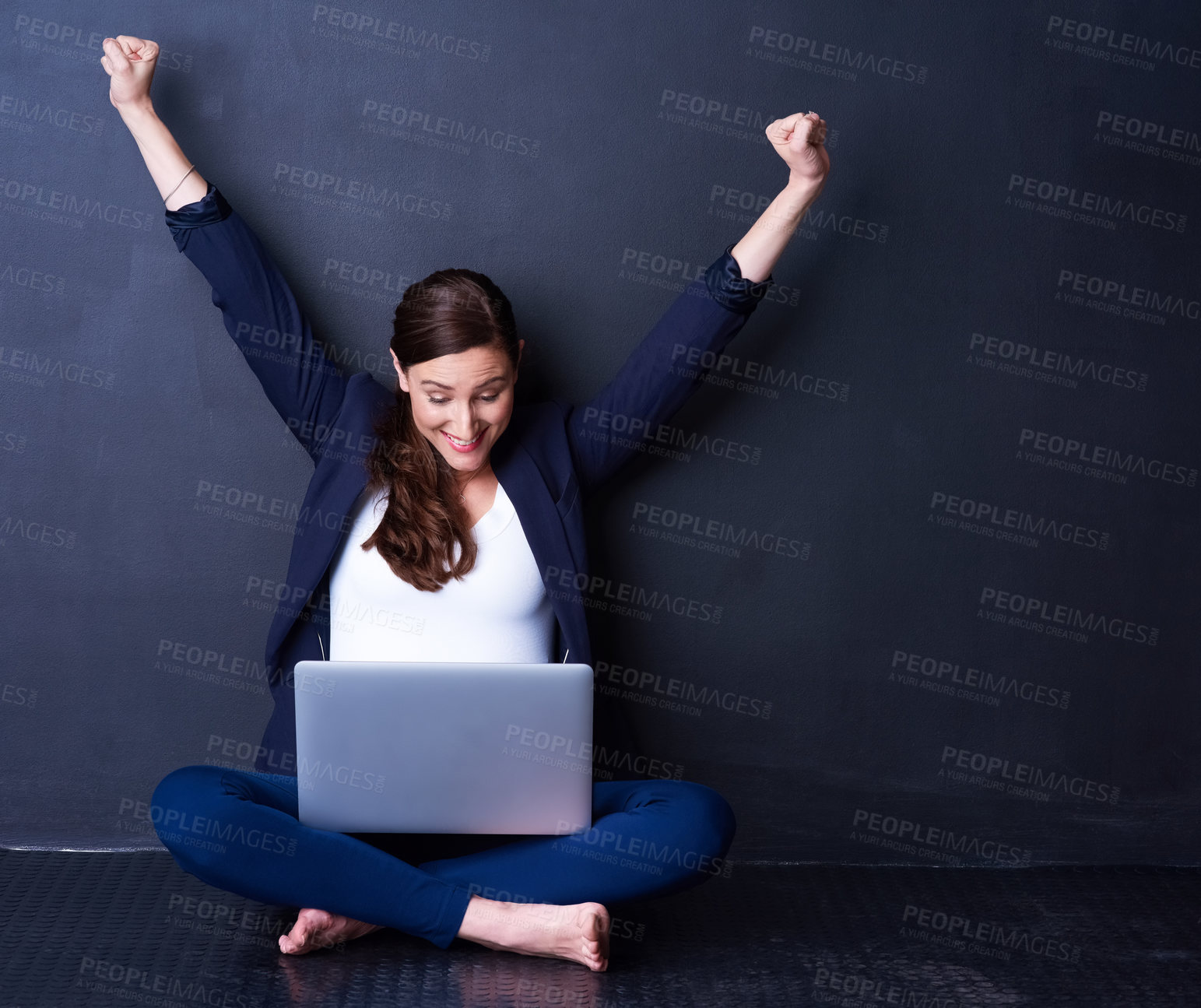 Buy stock photo Shot of a happy businesswoman looking at her laptop while raising her hands in excitement
