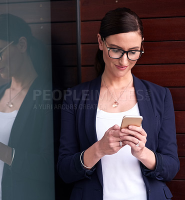 Buy stock photo Shot of a happy businesswoman using her smartphone next to a window in the office