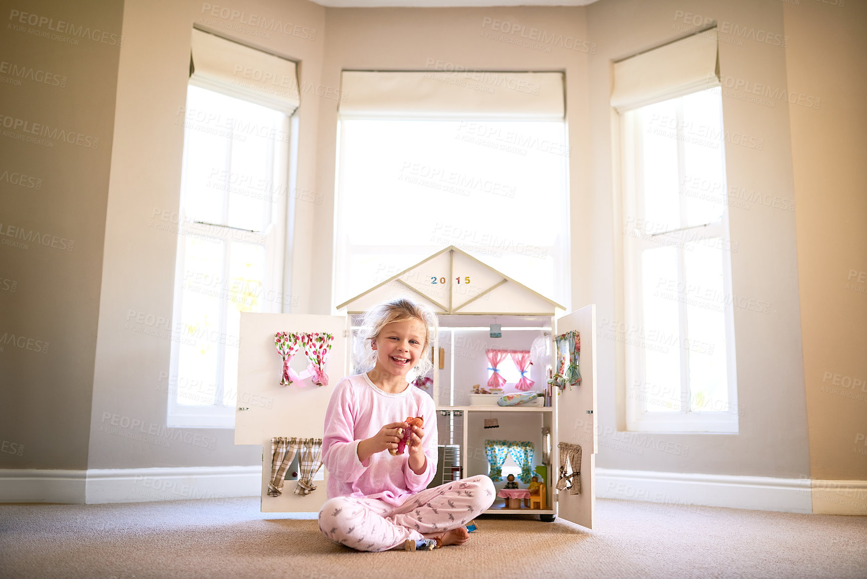 Buy stock photo Doll house, portrait and girl child in home playing with toys for growth, development and fun. Smile, sweet and young kid with 3d apartment figure in bedroom for game with happy and positive attitude