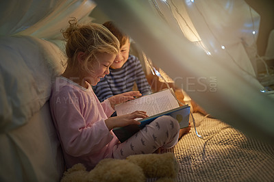 Buy stock photo Cropped shot of siblings reading a story under a blanket fort at home