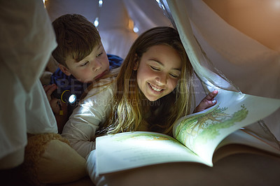 Buy stock photo Cropped shot of siblings reading a story under a blanket fort at home