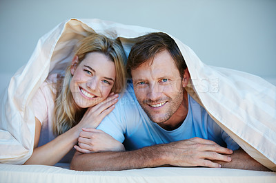 Buy stock photo Portrait of a young couple lying in bed together