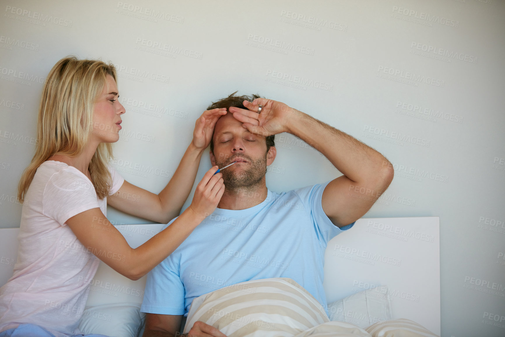 Buy stock photo Shot of a woman taking her husband's temperature