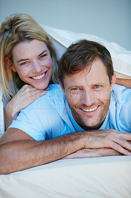 Buy stock photo Portrait of a young couple lying in bed together