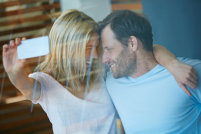 Buy stock photo Shot of a young couple taking a selfie at home