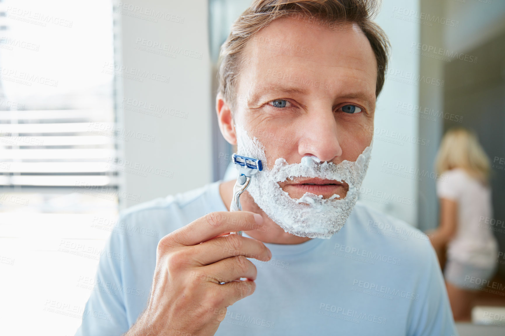 Buy stock photo Shot of a young man shaving his facial hair in the bathroom