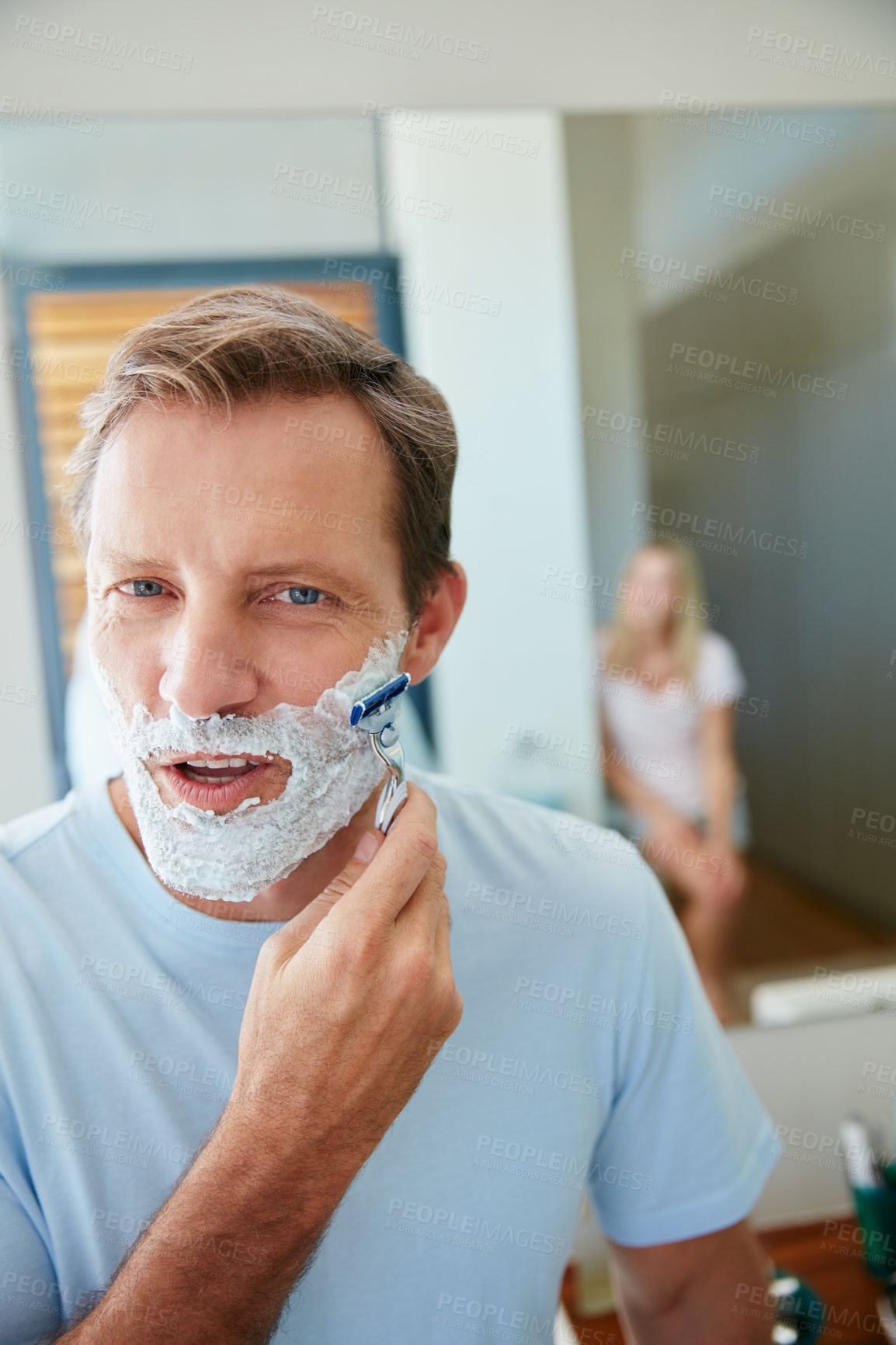 Buy stock photo Shot of a young man shaving his facial hair in the bathroom