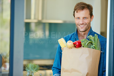 Buy stock photo Portrait of a happy man holding a bag full of healthy groceries