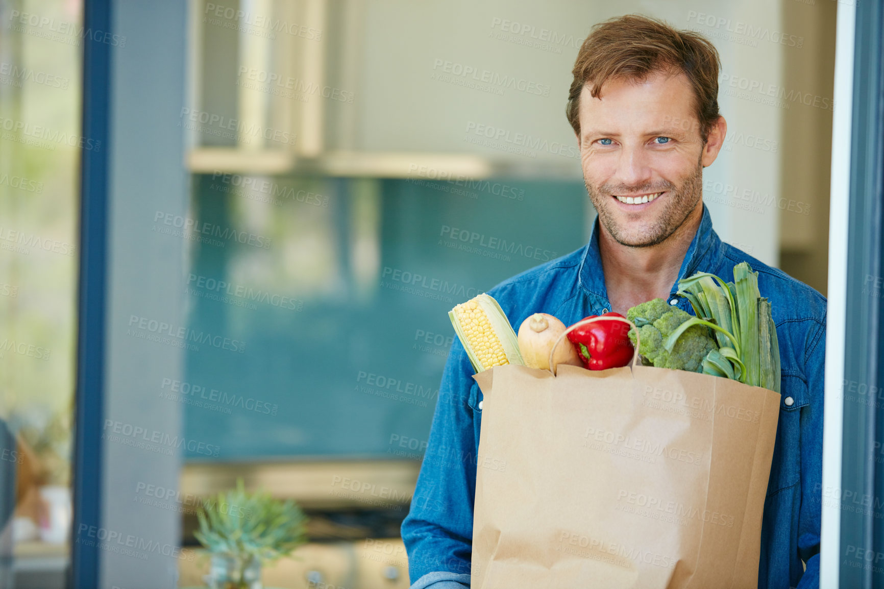 Buy stock photo Portrait of a happy man holding a bag full of healthy groceries