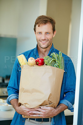 Buy stock photo Portrait of a happy man holding a bag full of healthy groceries