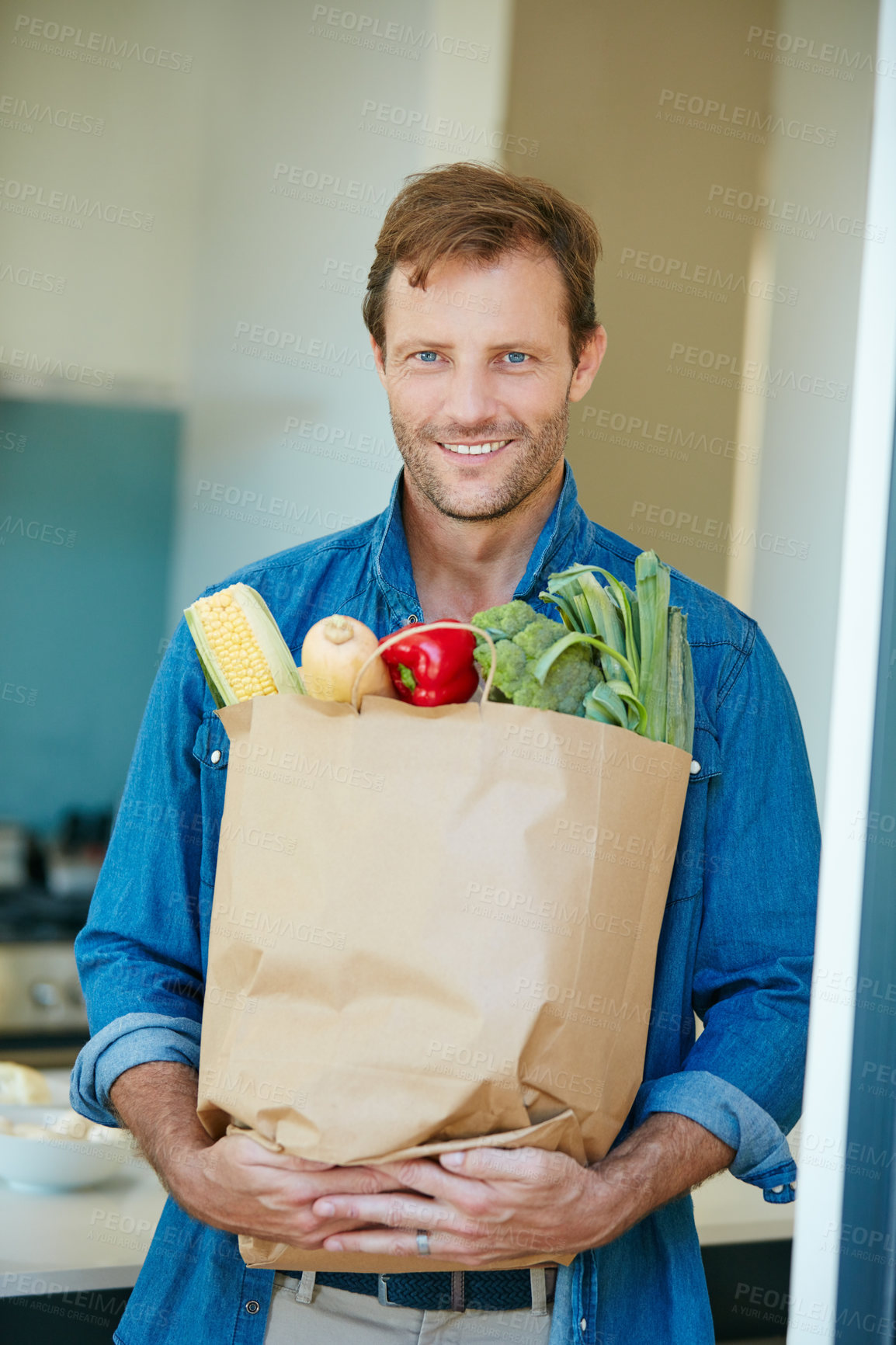 Buy stock photo Portrait of a happy man holding a bag full of healthy groceries