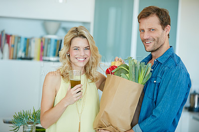 Buy stock photo Portrait of a happy couple holding a bag full of healthy groceries at home