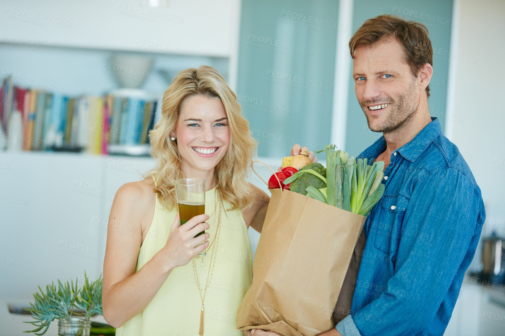 Buy stock photo Portrait of a happy couple holding a bag full of healthy groceries at home