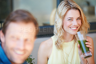Buy stock photo Portrait of a happy young woman enjoying a healthy smoothie with her husband at home