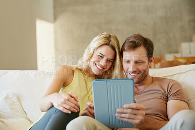 Buy stock photo Shot of a happy couple using a digital tablet together on a relaxing day at home