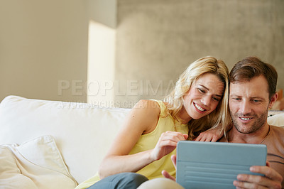 Buy stock photo Shot of a happy couple using a digital tablet together on a relaxing day at home