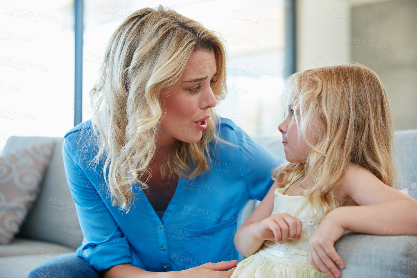 Buy stock photo Shot of a young mother talking to her daughter while sitting on the sofa at home