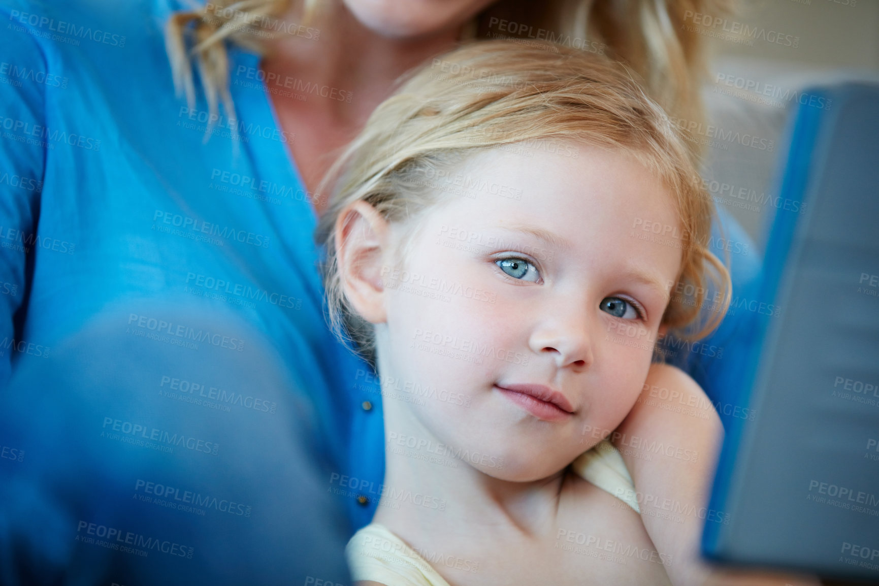 Buy stock photo Shot of a mother and her daughter watching something on a tablet while sitting on the sofa at home