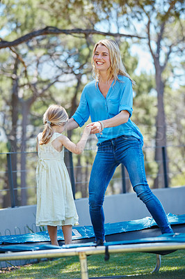 Buy stock photo Shot of a young mother playing on the trampoline with her daughter outside