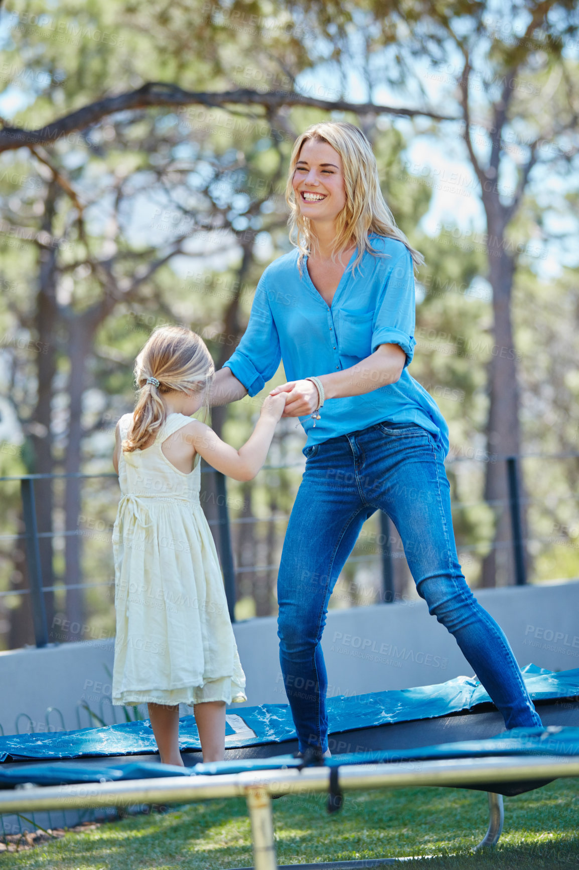 Buy stock photo Shot of a young mother playing on the trampoline with her daughter outside