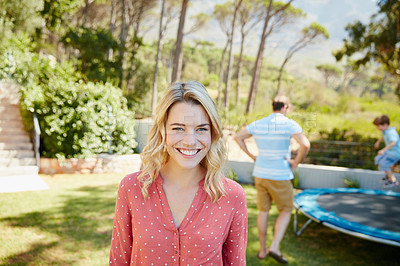 Buy stock photo Portrait of a young woman enjoying a day outside with her family in the background