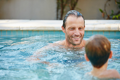 Buy stock photo Cropped shot of a father and son swimming in a pool together
