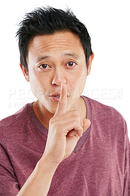 Buy stock photo Studio portrait of a young man holding a finger to his lips against a white background