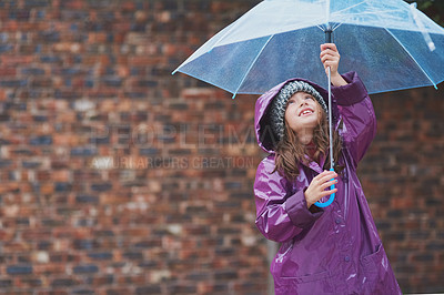 Buy stock photo Cropped shot of a little girl standing under an umbrella outside