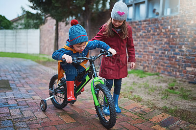 Buy stock photo Shot of a little girl teaching her brother how to ride a bicycle outside
