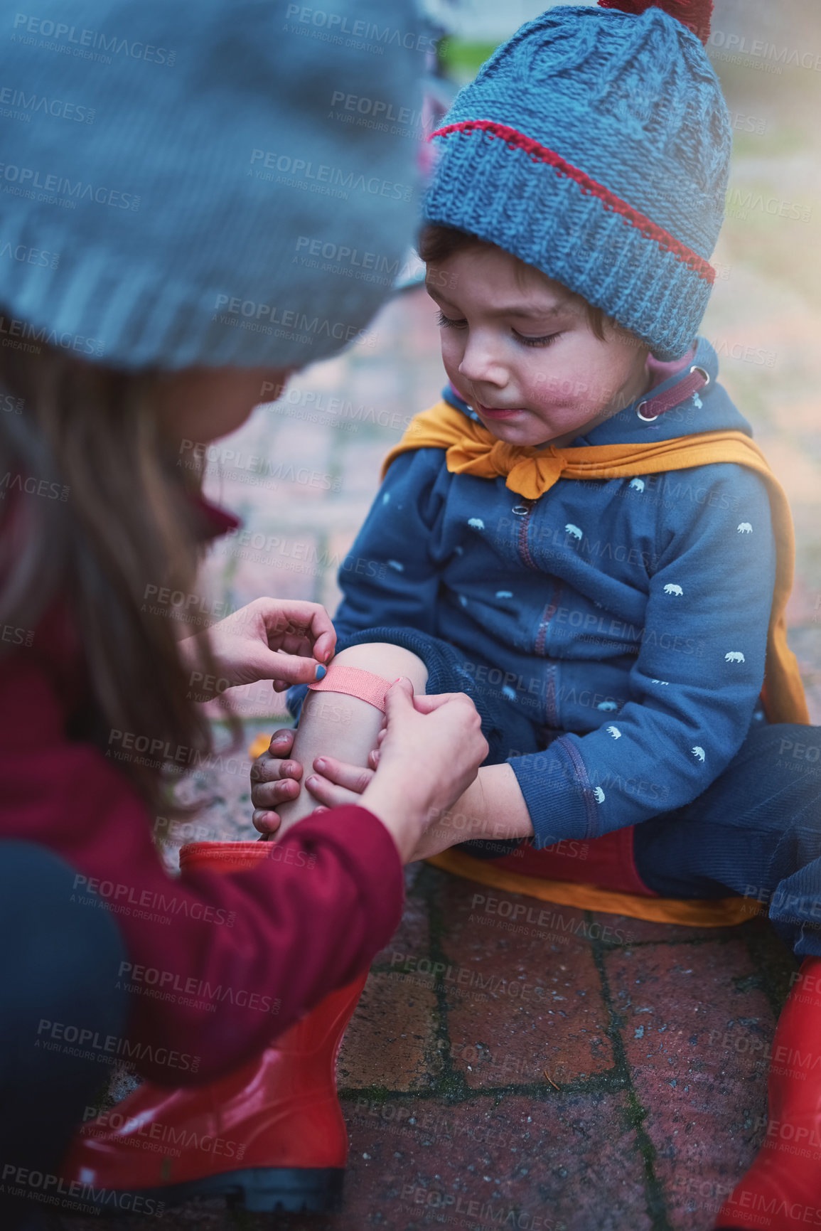 Buy stock photo Cropped shot of a young girl putting a plaster on her little brother's knee