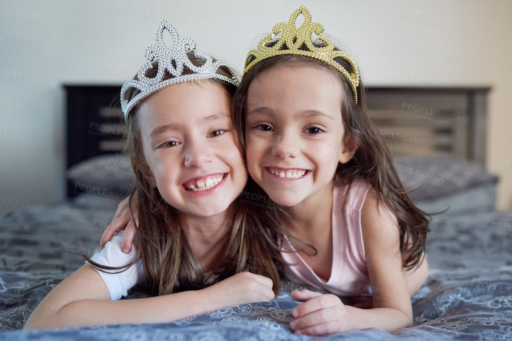 Buy stock photo Portrait of two little sisters lying on a bed together at home