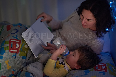 Buy stock photo Cropped shot of a little boy lying in bed while his mom reads a bedtime story