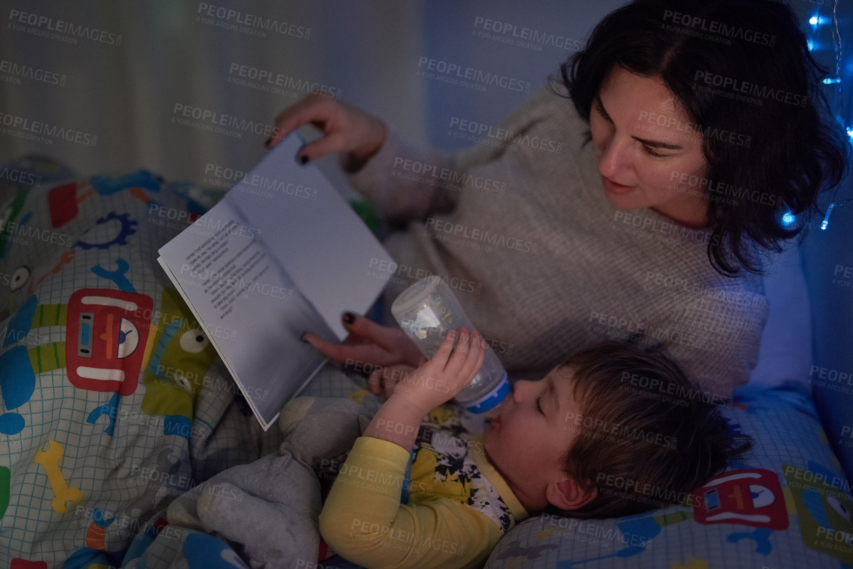 Buy stock photo Cropped shot of a little boy lying in bed while his mom reads a bedtime story