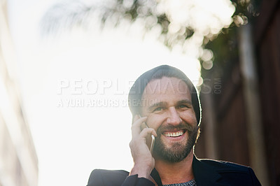Buy stock photo Cropped shot of a young man talking on a cellphone outside
