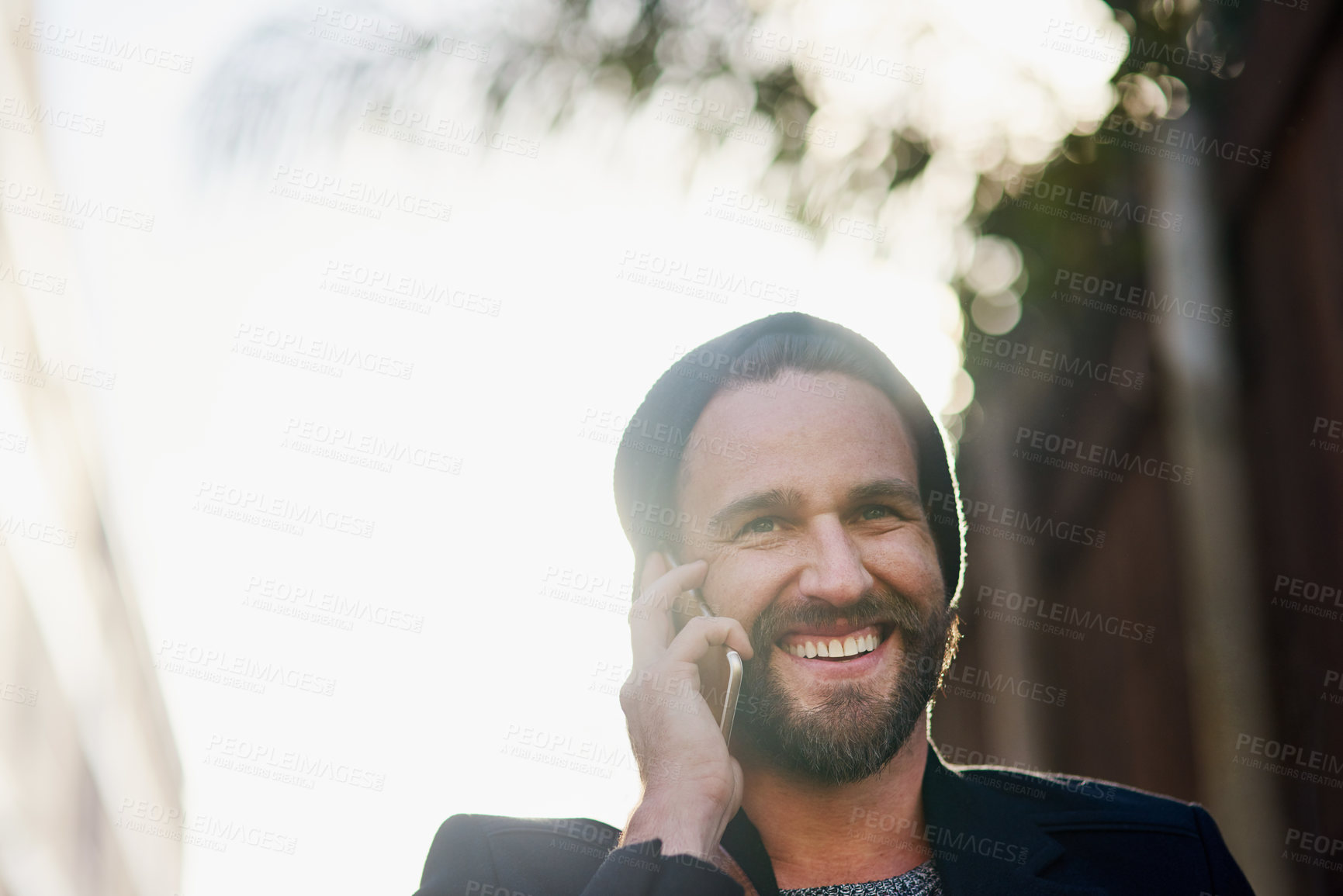 Buy stock photo Cropped shot of a young man talking on a cellphone outside