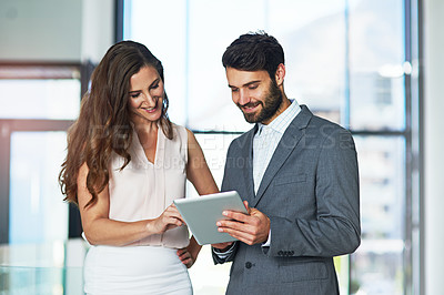 Buy stock photo Shot of a young businessman and businesswoman using a digital tablet together in an office