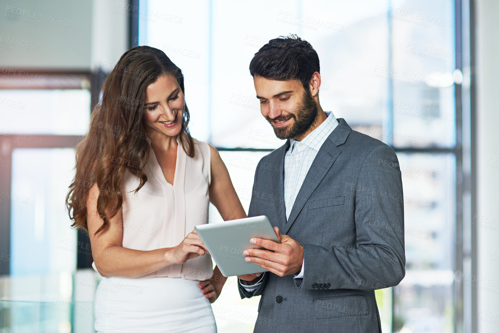 Buy stock photo Shot of a young businessman and businesswoman using a digital tablet together in an office