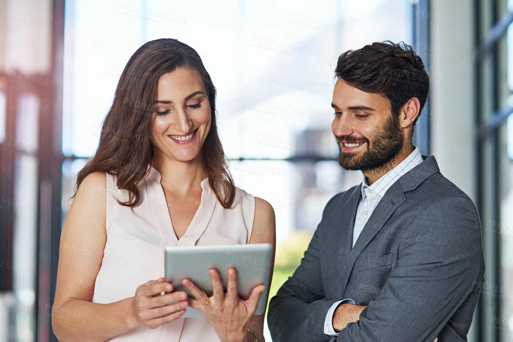 Buy stock photo Shot of a young businessman and businesswoman using a digital tablet together in an office