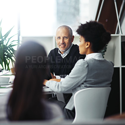Buy stock photo Portrait of a mature businessman sitting in a meeting with two colleagues