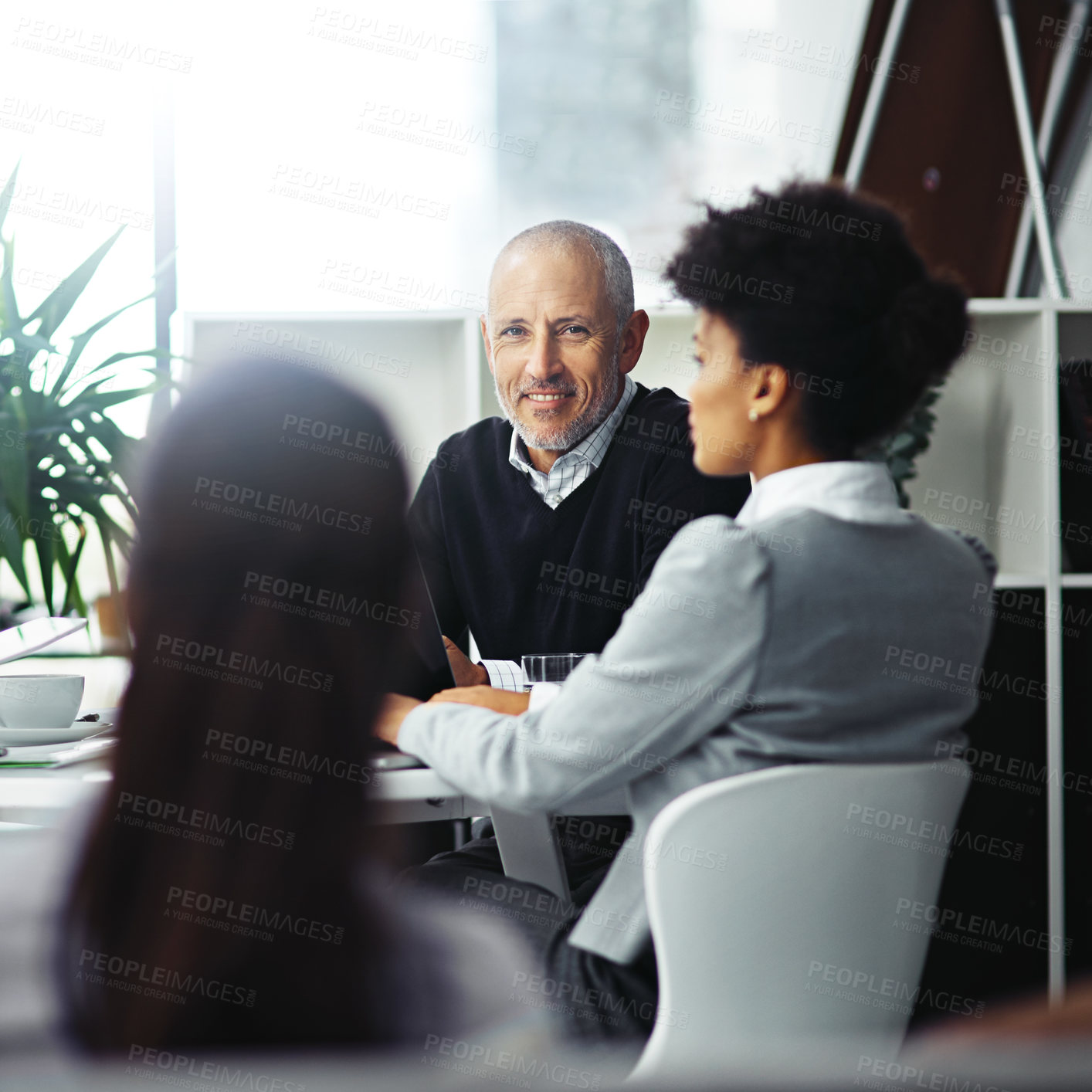 Buy stock photo Portrait of a mature businessman sitting in a meeting with two colleagues