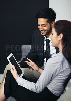 Buy stock photo Shot of two businesspeople talking together over a digital tablet while sitting in an office