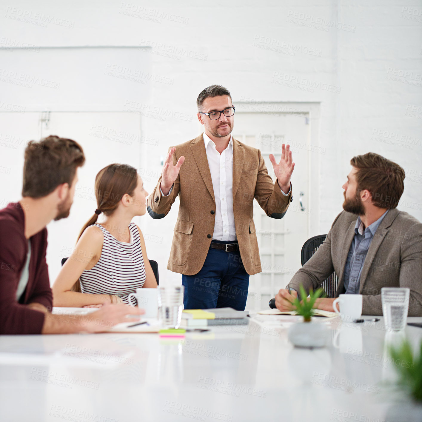 Buy stock photo Shot of a businessman giving a presentation to colleagues sitting at a table in a modern office